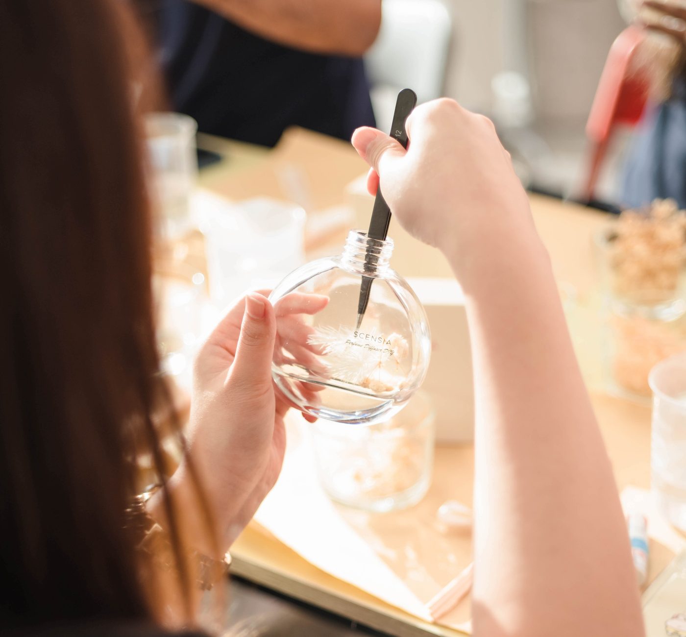 Guest filling a round perfume bottle at a workshop
